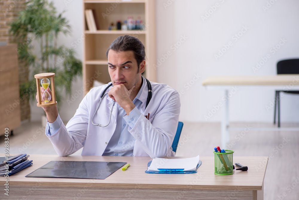Young male doctor in time management concept Young male doctor in time management concept