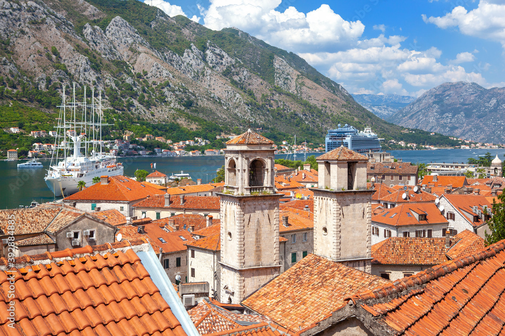 Two large white tourist ship in the bay. In the foreground is a city on the coast of the with tiled roofs. Kotor, Montenegro