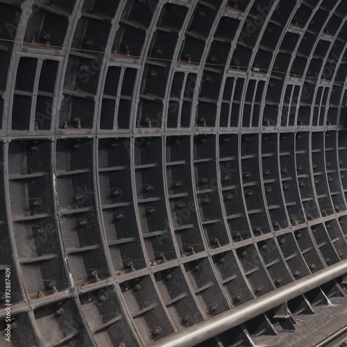 Dark dusty surface of deep-running underground tunnel with bolted joints of prefabricated reinforced lining for texture or abstract background. Structure of metro tunnel.