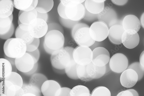Black and white blurred picture of Christmas lights, monochromatic abstract background.