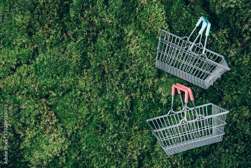 Top view of supermarket shopping basket on green grass, moss background. Minimalism style. Black friday sale, discount, shopaholism, ecology concept. Sustainable lifestyle, conscious consumption