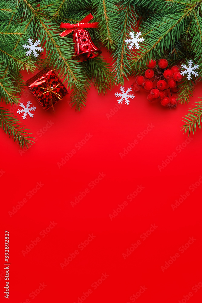 Christmas greeting card with fir tree branches, gift box, bell, white snowflakes and berries on red background. Vertical orientation, copy space for text Christmas greeting card with fir tree branches, gift box, bell, white snowflakes and berries on red background. Vertical orientation, copy space for text