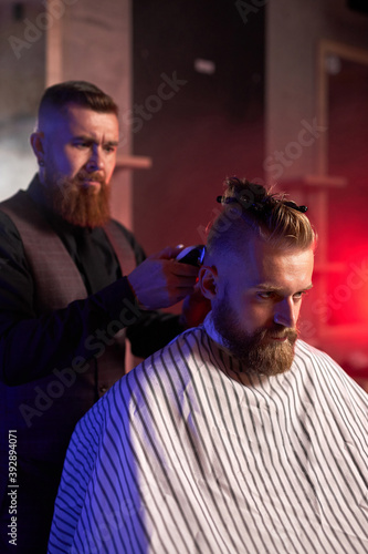 haircut at the hairdresser, in salon. barber male cuts the hair on the handsome young client's head, the process of creating hairstyles for men by professional