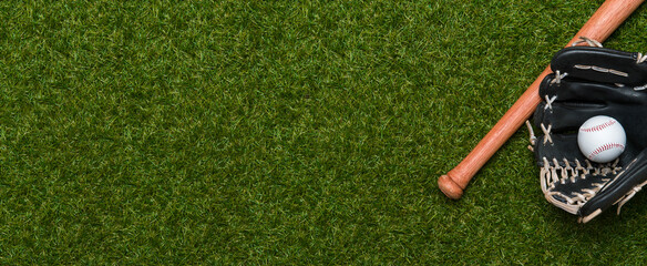 Baseball bat, glove and ball on green grass field.  Sport theme background with copy space for text and advertisment