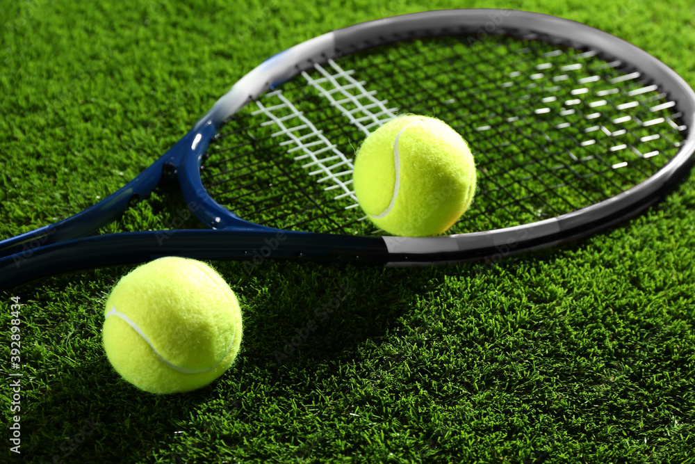 Tennis racket and balls on green grass. Sports equipment
