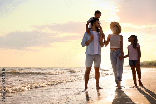 Canvas Print Happy family walking on sandy beach near sea