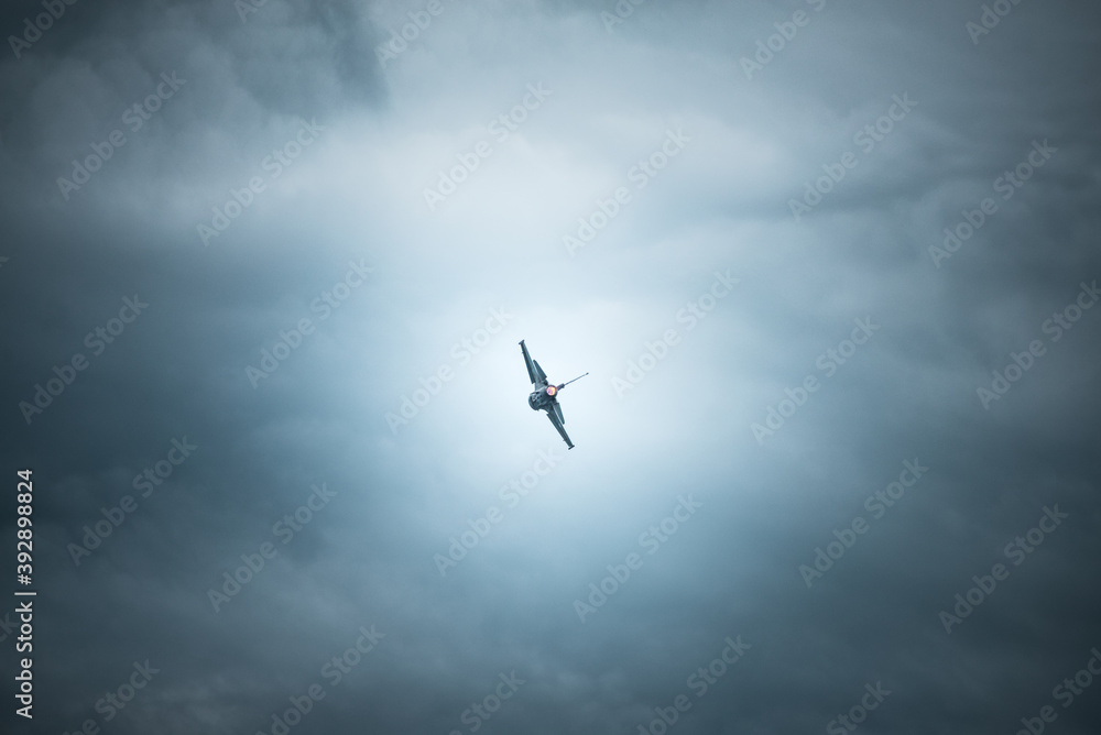 Obraz premium fighting jet f-16 in the cloudy sky ready to disappear into the horizon.