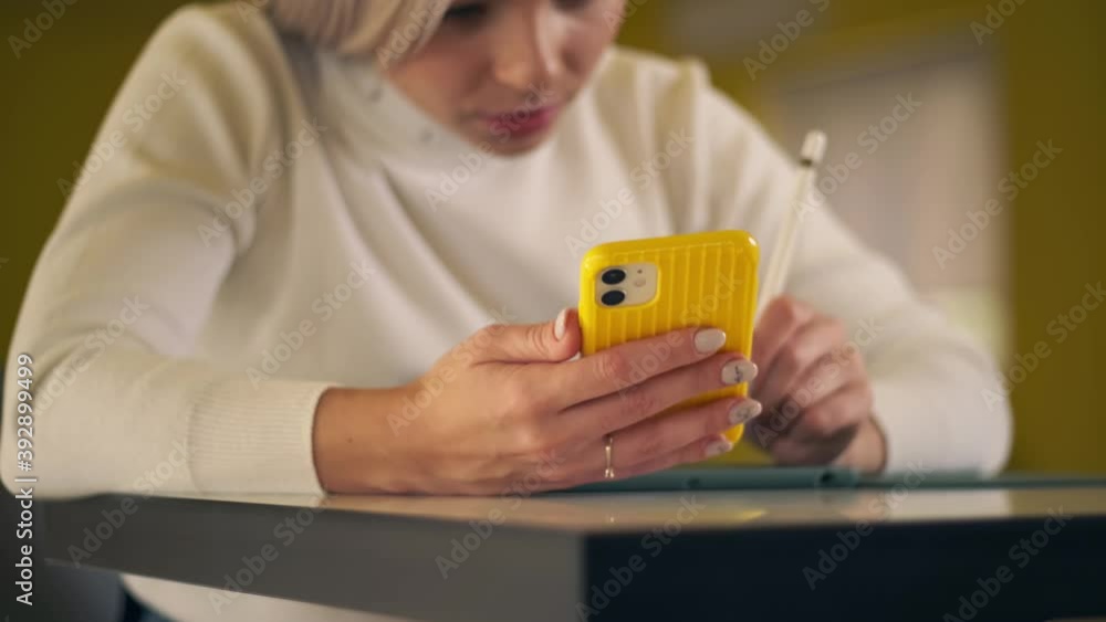 Close up shot of young woman using mobile phone and digital tablet for lesson online during quarantine Covid-19. Girl working on phone and digital tablet for work using digitized pen in home office Close up shot of young woman using mobile phone and digital tablet for lesson online during quarantine Covid-19. Girl working on phone and digital tablet for work using digitized pen in home office