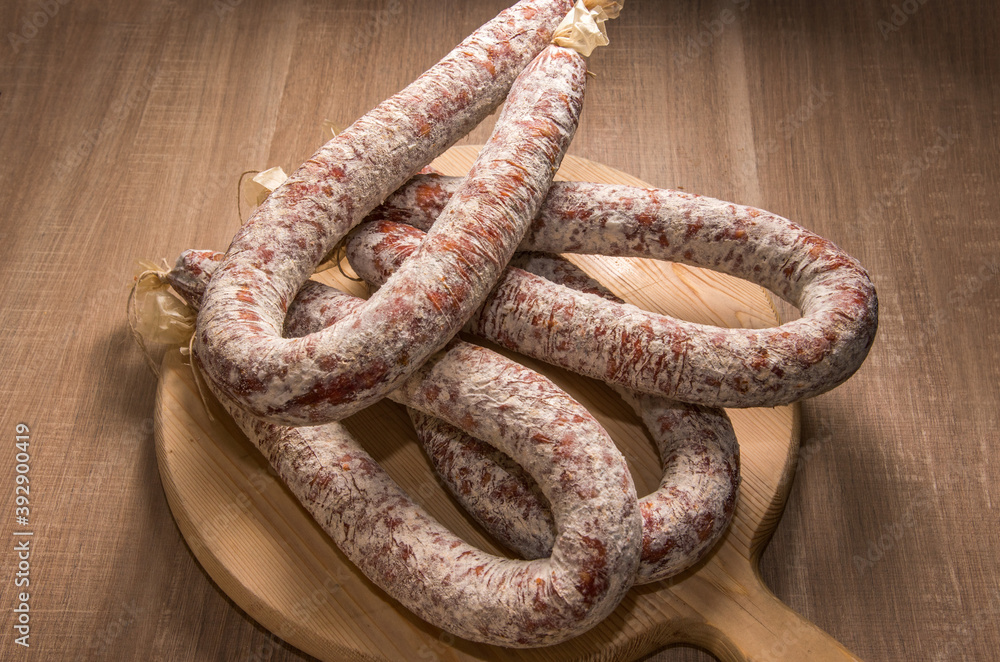 Italian spicy salami on wooden cutting board Italian spicy salami on wooden cutting board