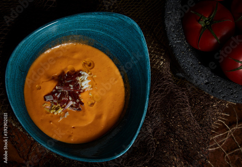 Typical Spanish salmorejo cream with ham and egg on wooden table. Top view. photo