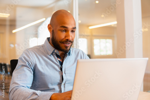 Focused black business man working and typing in laptop in the office. Executive, worker, specialist, corporate concept.