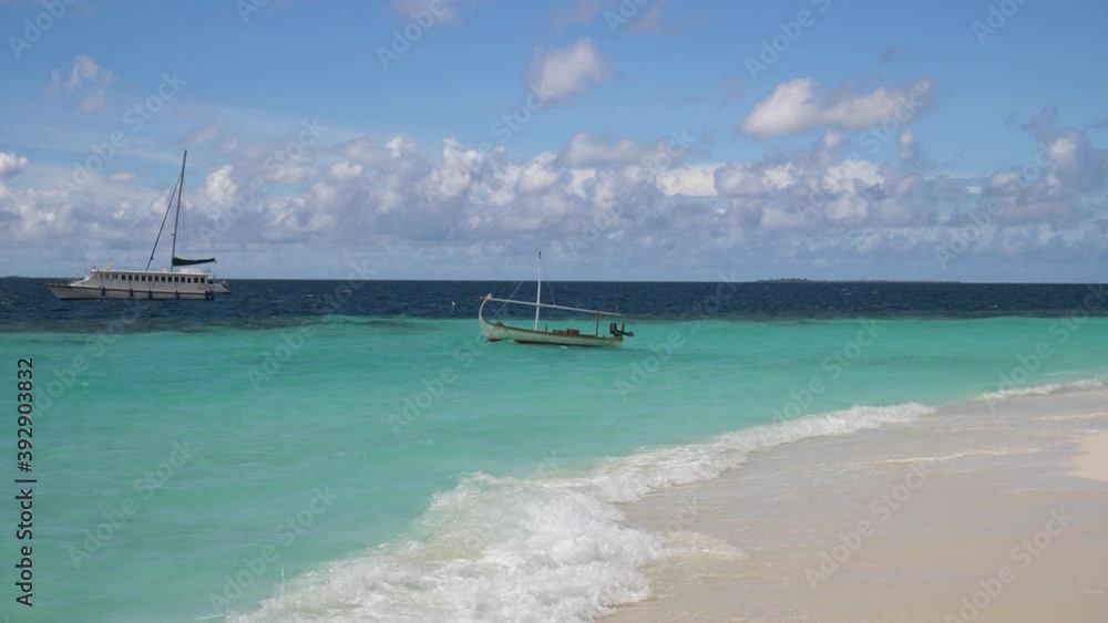 Boats anchored just off shore from beach, staying in place despite waves Boats anchored just off shore from beach, staying in place despite waves