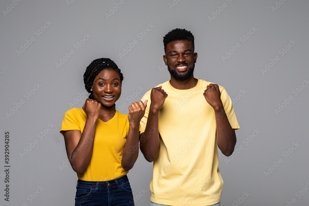 Overjoyed african American man and woman happy for win, excited ethnic couple in spectacles feel overjoyed receiving good news being successful isolated on grey studio background Overjoyed african American man and woman happy for win, excited ethnic couple in spectacles feel overjoyed receiving good news being successful isolated on grey studio background