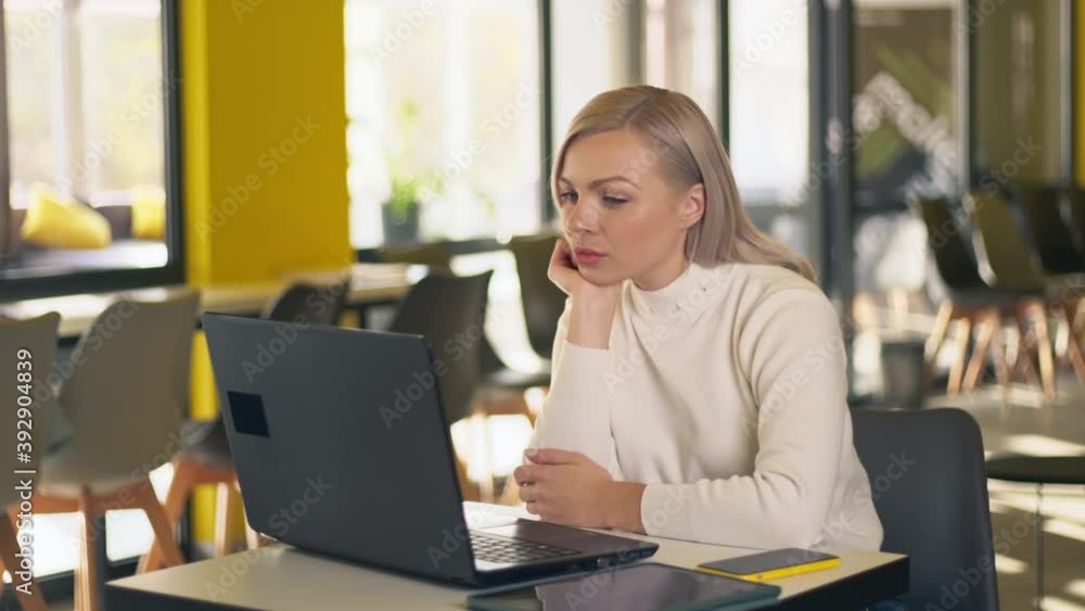 Young woman sitting using laptop for online study or work in home. Caucasian girl reading laptop screen for social media studying or working online at home. Young woman sitting using laptop for online study or work in home. Caucasian girl reading laptop screen for social media studying or working online at home.