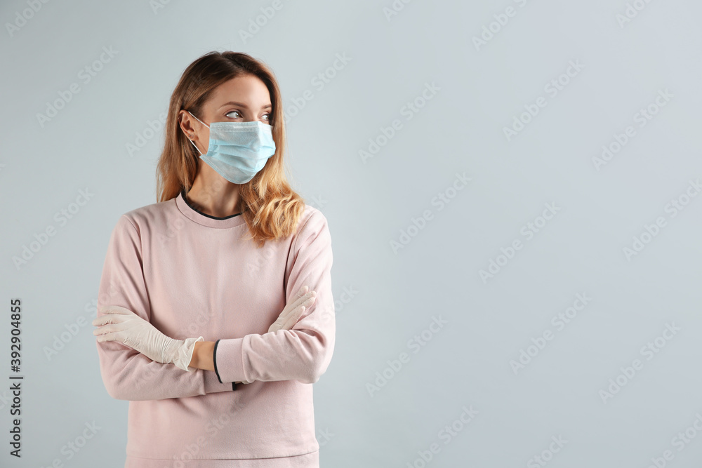 Young woman in medical gloves and protective mask on grey background. Space for text Young woman in medical gloves and protective mask on grey background. Space for text