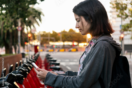 woman taking a bike with a phone in public parking