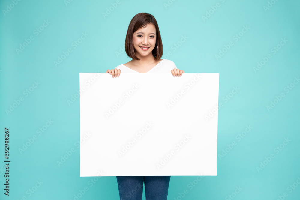 Young asian woman showing and holding blank white billboard isolated on green background Young asian woman showing and holding blank white billboard isolated on green background