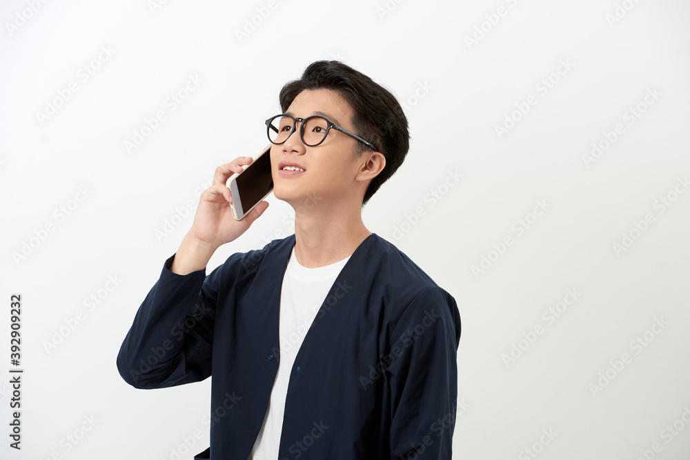 Young Asian man taling on phone while standing over white background. Young Asian man taling on phone while standing over white background.