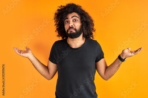 doubtful arab male is misunderstanding, show his incomprehension expression at camera, isolated over orange background