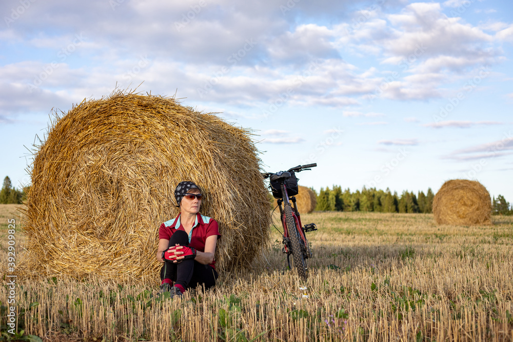 girl cyclist resting sitting on the ground by a haystack girl cyclist resting sitting on the ground by a haystack
