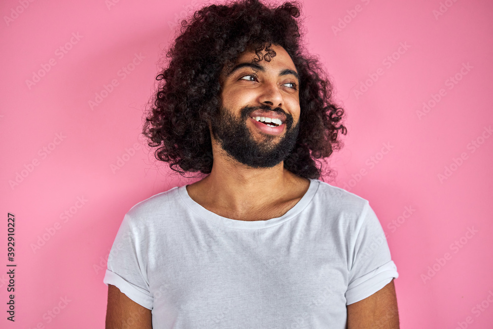 portrait of cheerful positive male of arabic appearance looking away laughing, he listen to joke, have fun with someone, isolated over pink background portrait of cheerful positive male of arabic appearance looking away laughing, he listen to joke, have fun with someone, isolated over pink background