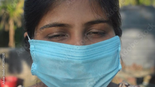 Smiling face wearing mask. Woman smiling wearing a face mask. Close up Front view of a happy Indian woman wearing a face mask smiling and looking at camera. Healthcare medicine background India.