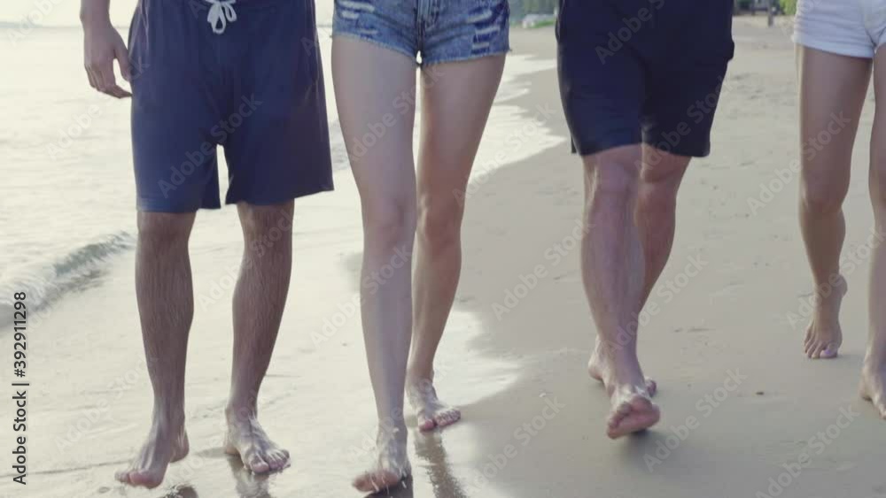 Close up feet of multiethnic couple or friends in casual summer wear walking together in the sunset at beach background. men in shirtless wearing sunglasses and women in tank top. outdoor relaxing Close up feet of multiethnic couple or friends in casual summer wear walking together in the sunset at beach background. men in shirtless wearing sunglasses and women in tank top. outdoor relaxing
