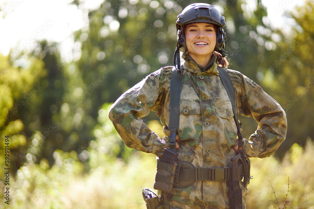 portrait of positive caucasian soldier woman smiling at camera, in nature, posing. war, hunting, military concept