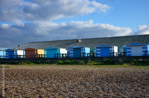 Colorful wooden beach huts at the coast of the seaside town Whitstable in Kent, England, blue sky with clouds background, a sunny day
