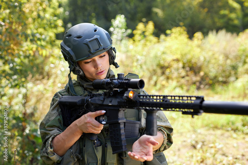 brave caucasian woman is engaged in hunting weapon gun or rifle, wearing military suit. target shot. female hunter in wild forest, nature. successful hunt. hunting sport concept