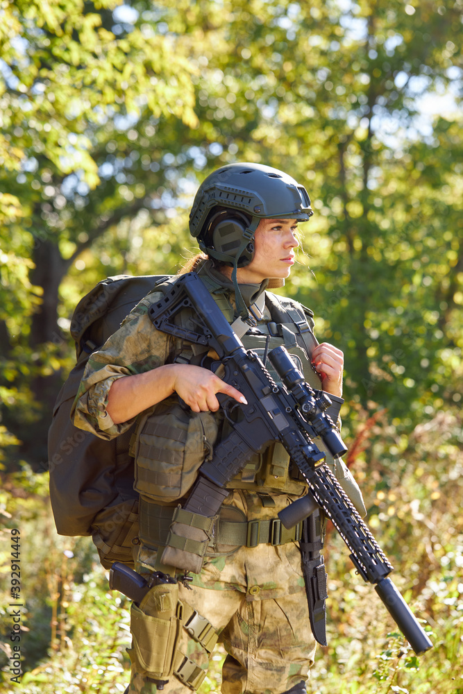 young caucasian military woman holds a gun in her hand in nature, she is going to hunt, hunting in forest is a hobby. game with weapons