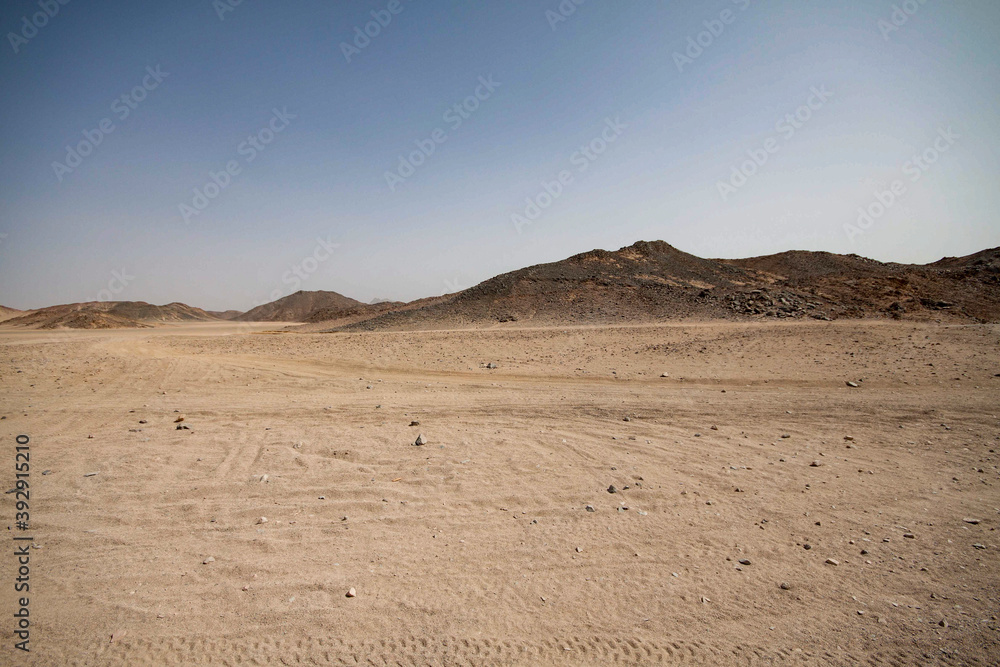A view of a sandy desert with mountains and the pyramids in the background A view of a sandy desert with mountains and the pyramids in the background