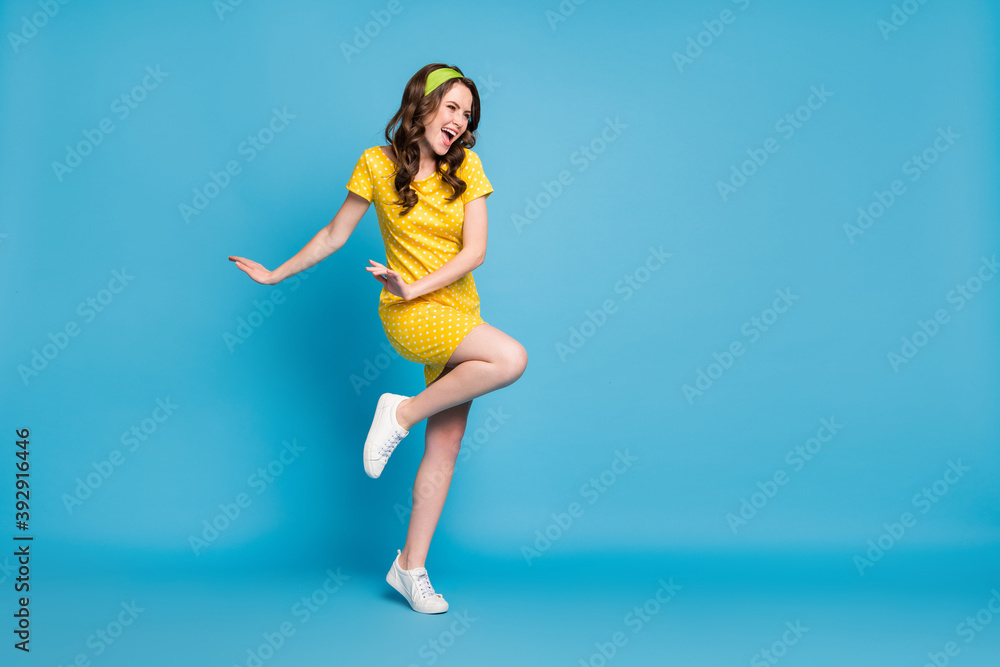 Full body photo of excited lady look in empty space wear polka-dot skirt isolated over blue color background