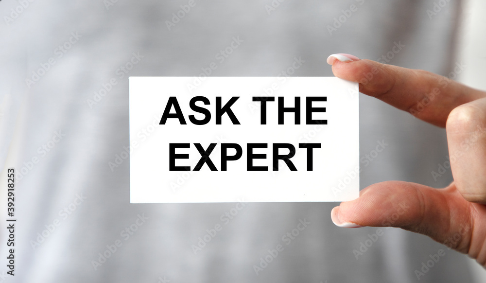 The businessman holds a business card with the text ASK THE EXPERT. The businessman holds a business card with the text ASK THE EXPERT.