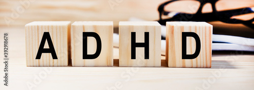 On wooden cubes the text of ADHD, next to the pen, coins, reports.