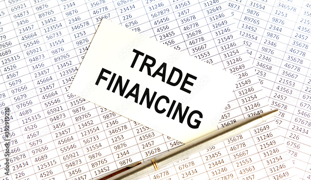 Obraz premium On the business card the text of TRADE FINANCING, next to the pen, the background are reports.