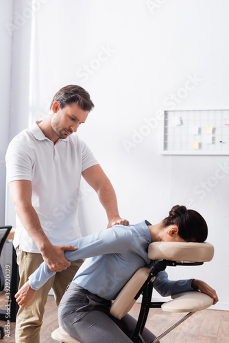 Focused masseur doing seated massage of arm for brunette businesswoman in office © LIGHTFIELD STUDIOS