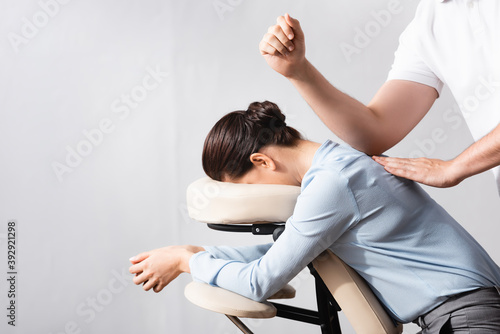 Schilderij op canvas Side view of masseur massaging woman back with elbow, sitting on massage chair o