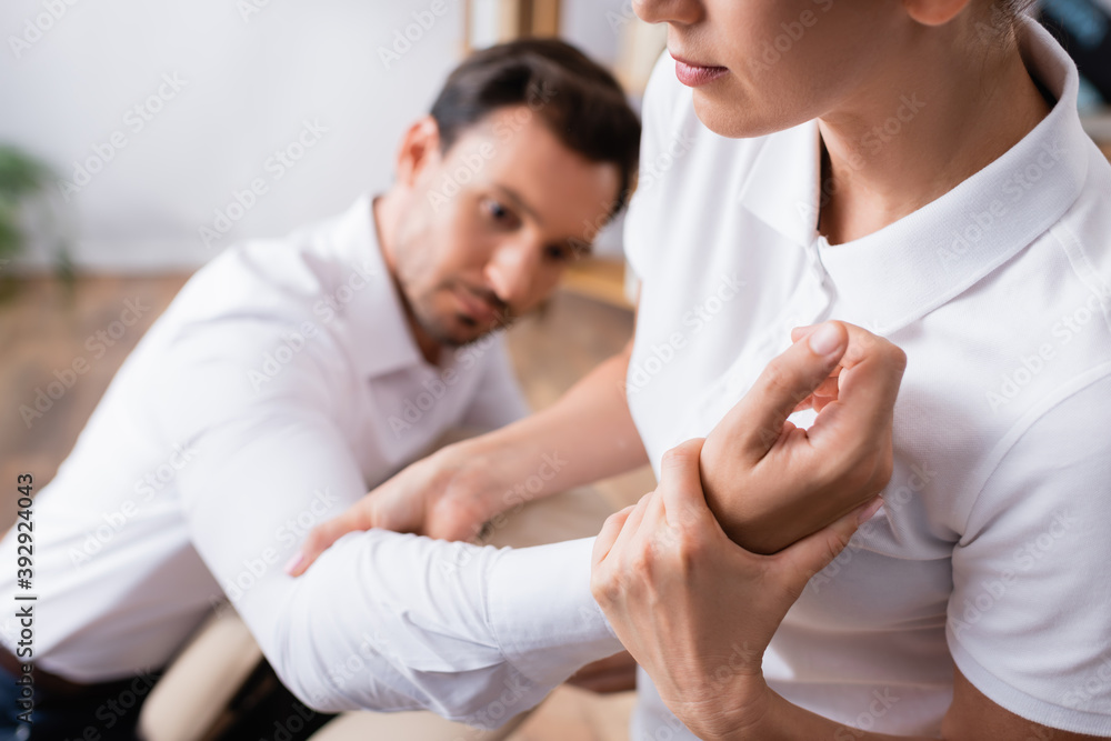 Masseuse doing arm massage for businessman on blurred background Masseuse doing arm massage for businessman on blurred background