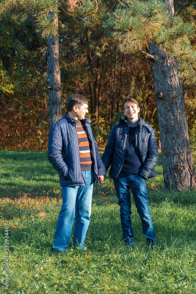 teenager and father posing in autumn park, beautiful nature