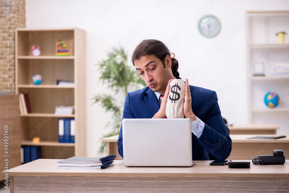 Young male employee holding moneybag in the office Young male employee holding moneybag in the office
