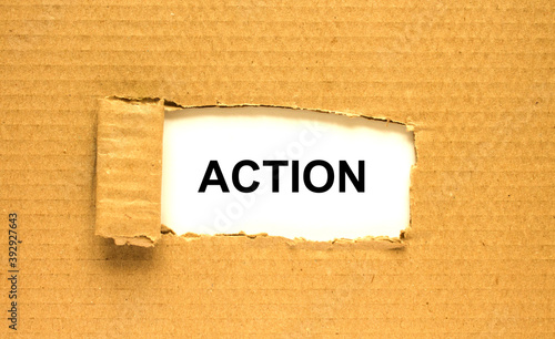 The word Action appearing behind torn brown paper