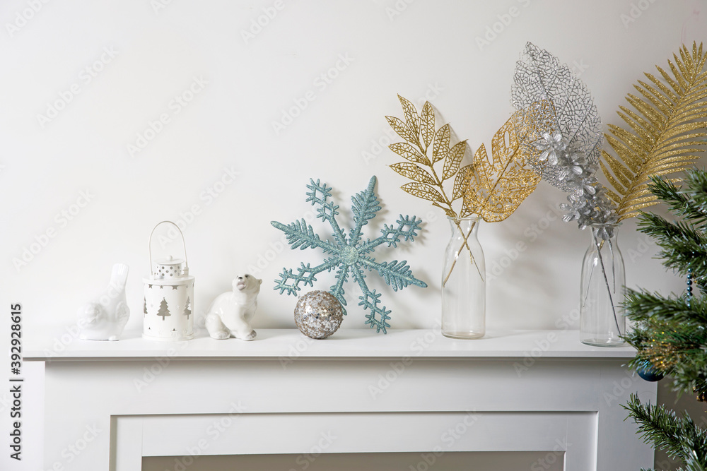Christmas decoration: blue faux glitter snowflake, candle holder and porcelain white figurine bullfinch bird stand on the console. Christmas decoration: blue faux glitter snowflake, candle holder and porcelain white figurine bullfinch bird stand on the console.