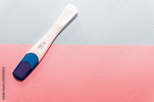 Positive pregnancy test on top of a blue and pink background. Pregnancy test. Pregnancy concept.