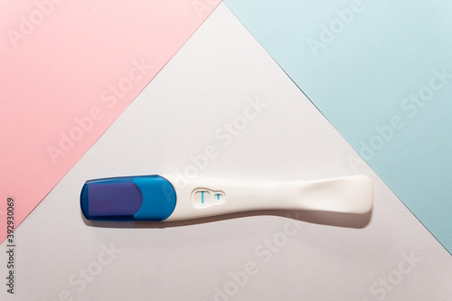 Positive pregnancy test on a blue, pink and white background. Pregnancy test. Pregnancy concept.