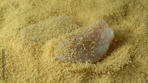 Close-up of chicken fillet falling into a breadcrumbs for frying in a pan for cooking nuggets. The concept of delicious traditional european food. Slow motion