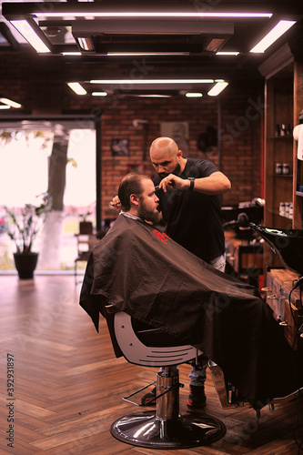 Brutal barber shaves a man in a barbershop © Владимир Стороженко