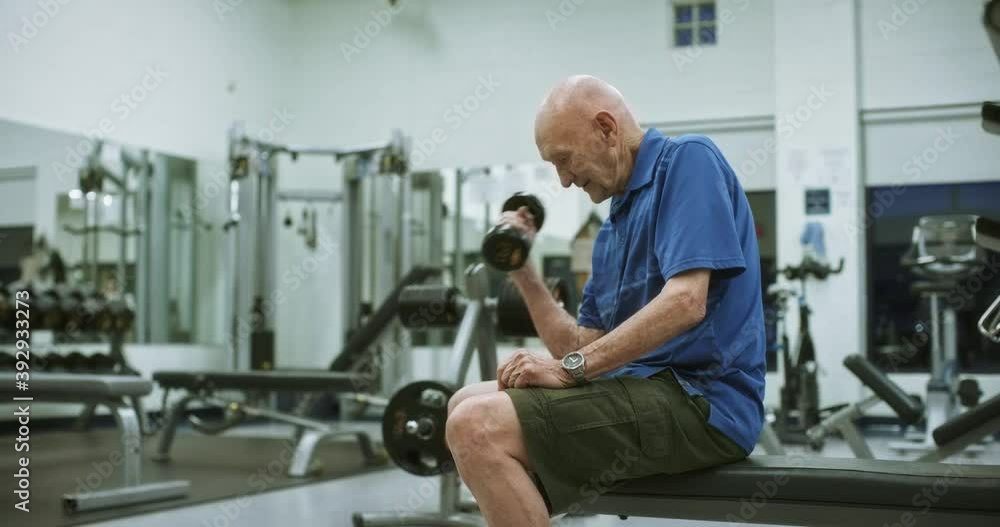 Medium shot, elderly man lifts dumbbell at gym Medium shot, elderly man lifts dumbbell at gym