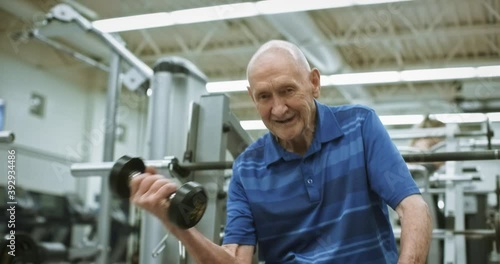Tilt up, elderly man lights weights at gym