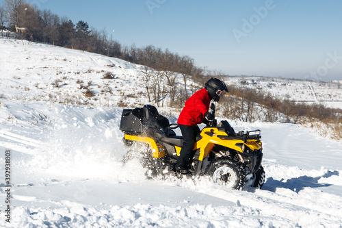 Extremal driver driving his ATV 4wd quad bike stand in heavy snow with deep wheel track.